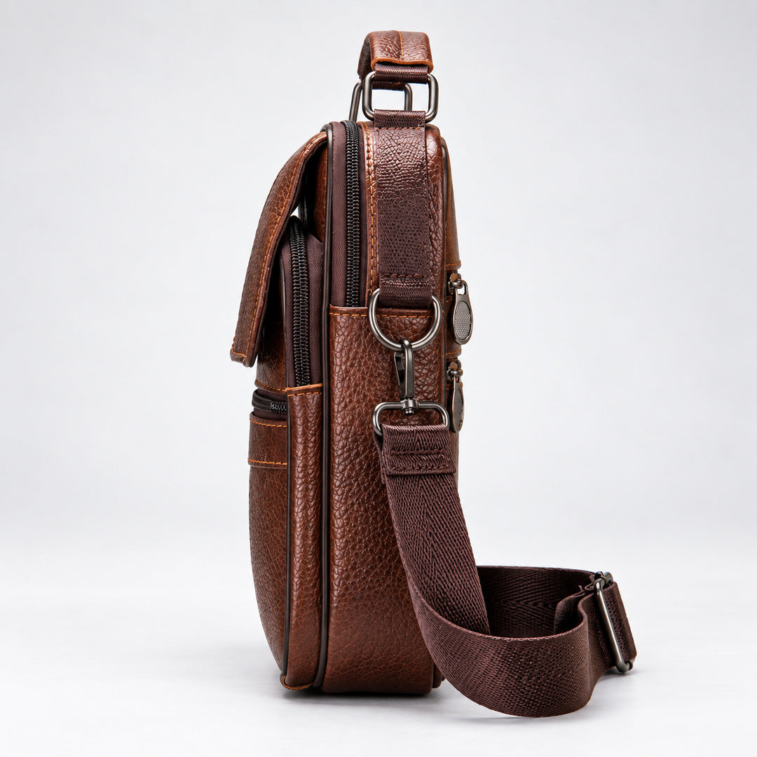 A brown textured leather crossbody bag with a matching adjustable shoulder strap, shown from a side profile view against a light gray studio background.