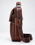 A brown textured leather crossbody bag with a matching adjustable shoulder strap, shown from a side profile view against a light gray studio background.