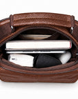 A brown textured leather zippered pouch or organizer shown open, revealing storage compartments filled with a tablet, notebook, and other small accessories, on a plain white background.