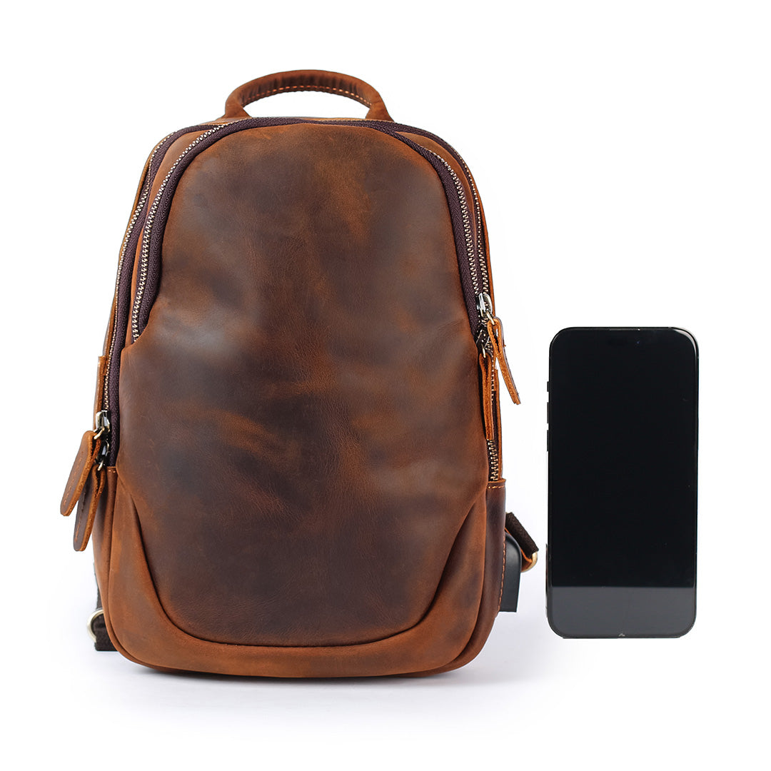 Brown leather men’s sling bag front view with phone for size comparison