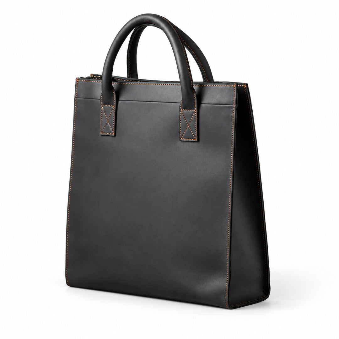 Minimalist black full-grain leather tote at an angle showing its tall shape and stitched side panel
