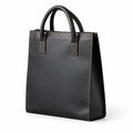 Minimalist black full-grain leather tote at an angle showing its tall shape and stitched side panel