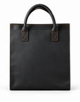 Minimalist black full-grain leather tote with rounded handles and brown contrast stitching