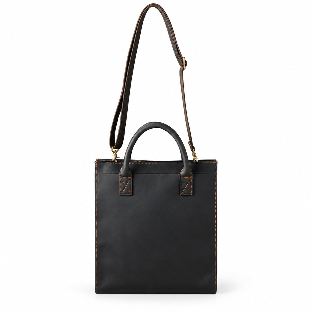Minimalist black full-grain leather tote with an adjustable shoulder strap and metal clips
