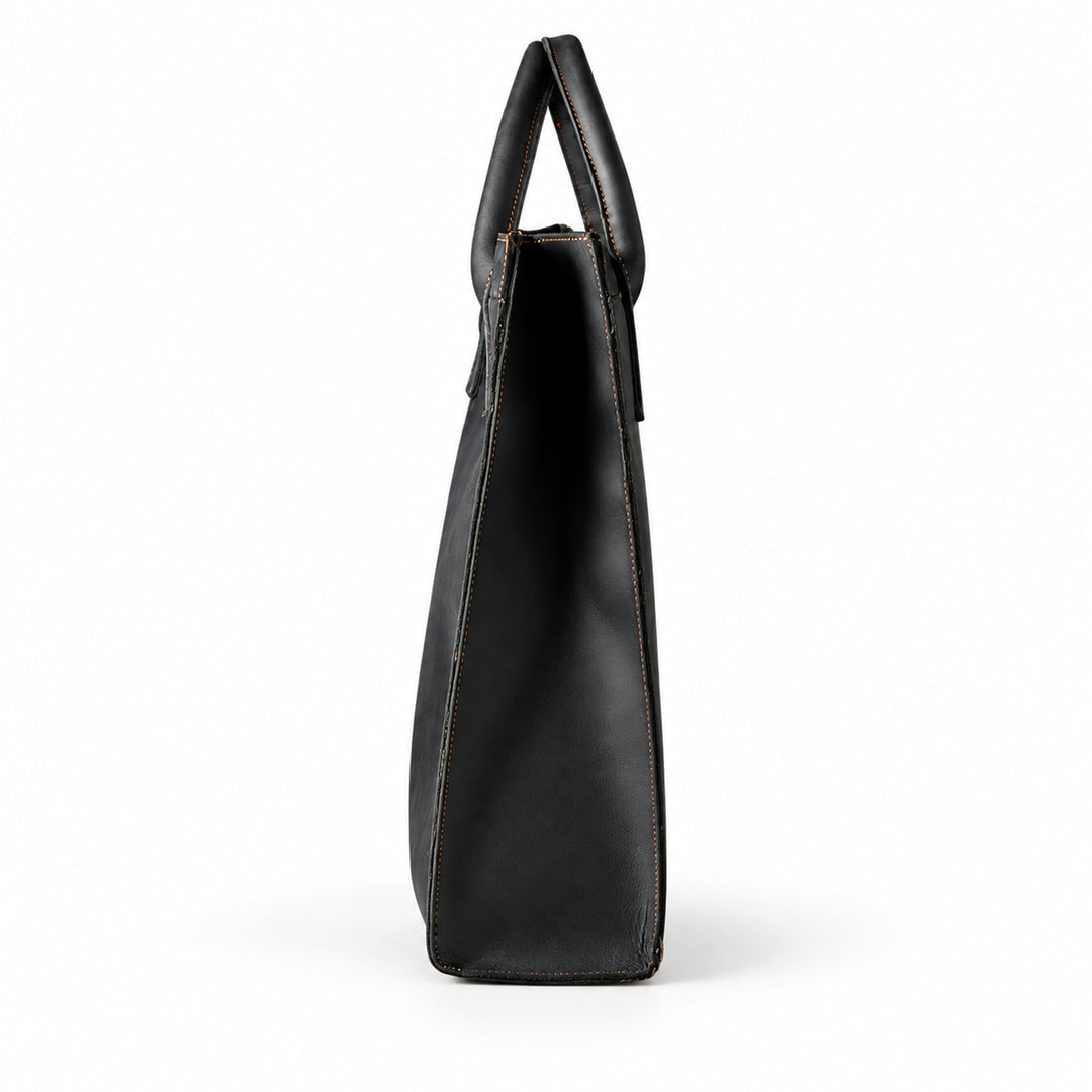 Minimalist black full-grain leather tote side profile with a narrow gusset and rounded handles
