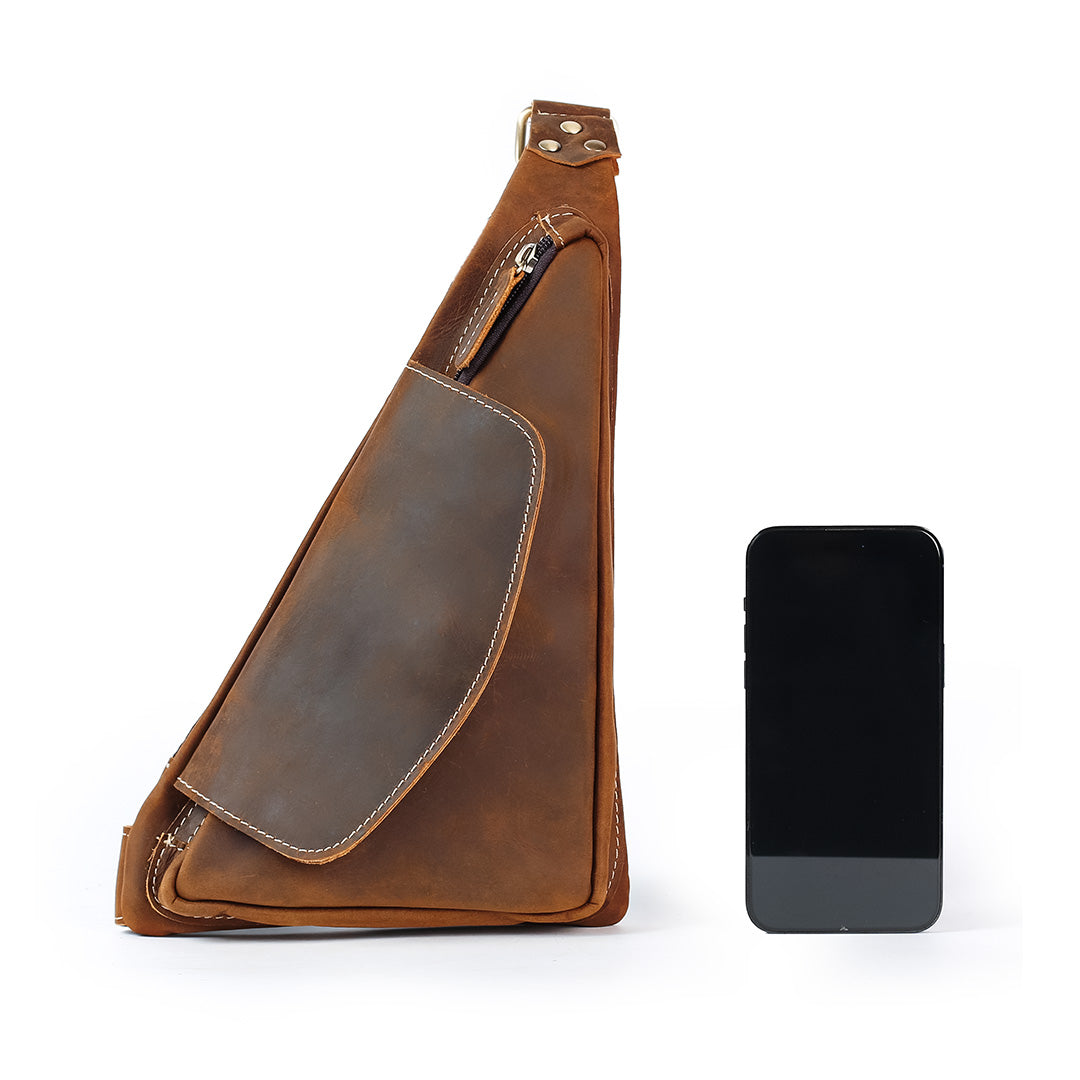 Brown leather sling bag next to a smartphone on a white background