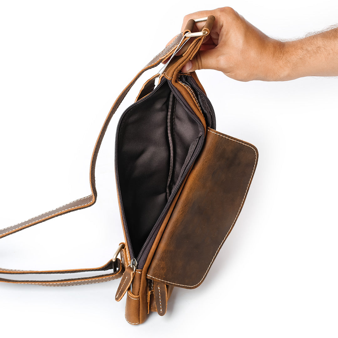 Brown leather handbag held open by a hand on a white background