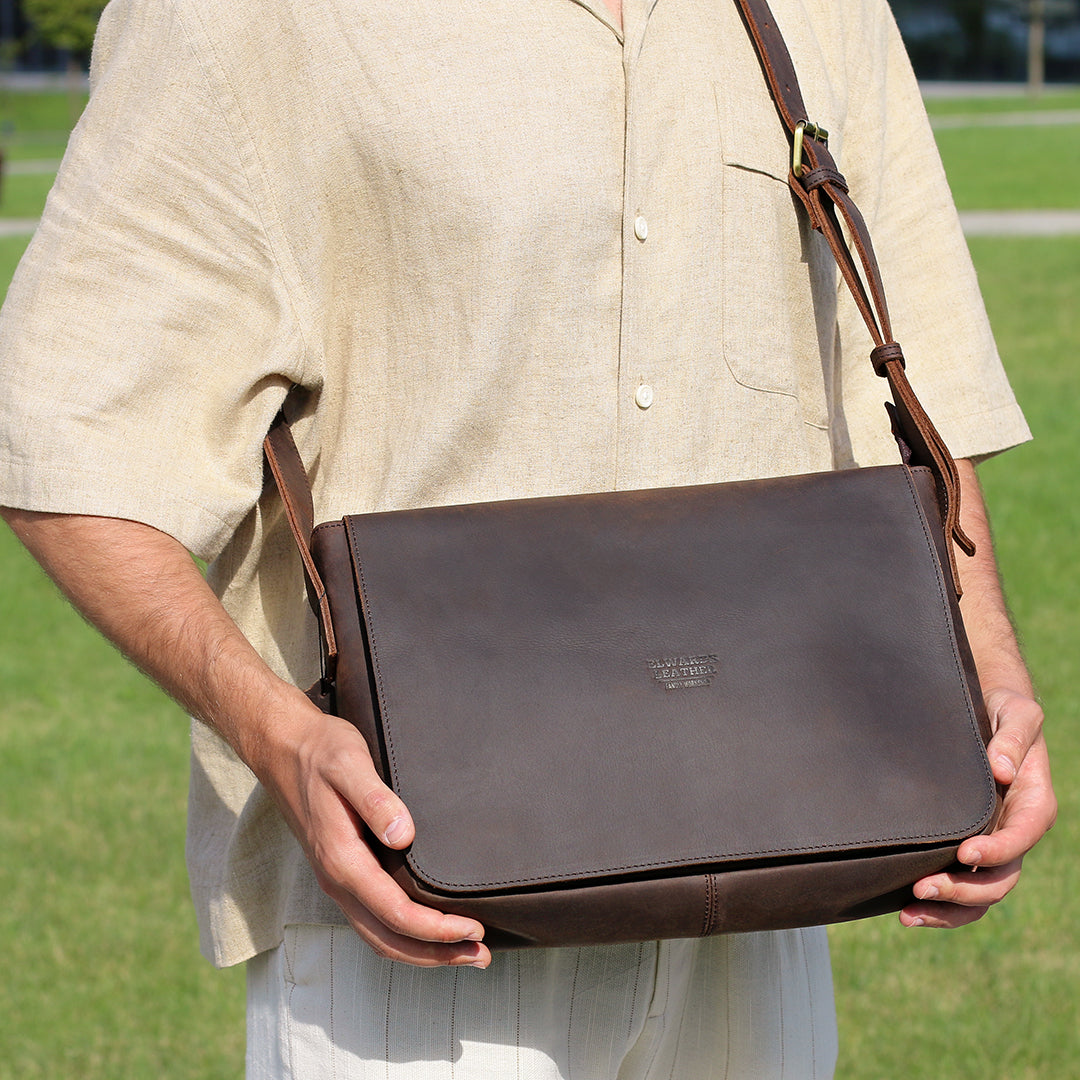 Model holding a dark brown leather satchel bag, showcasing its size and practicality