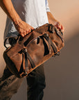 Model holding a vintage leather backpack, highlighting its compact size and elegant design for travel.