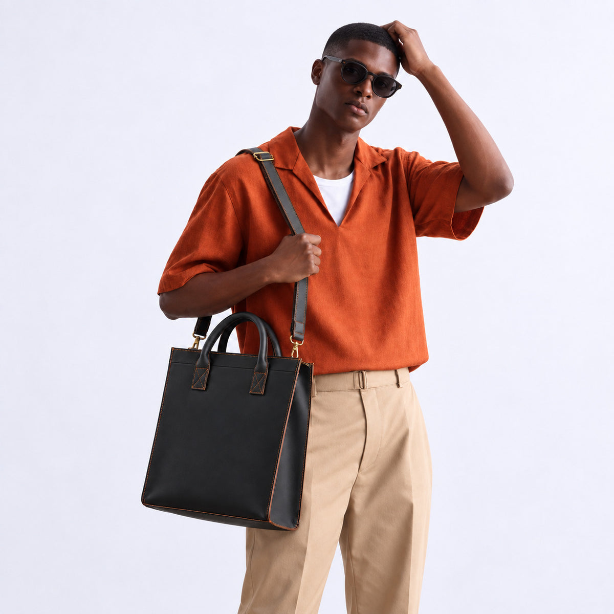 Modern black leather tote bag for men with dual top handles, contrast stitching and adjustable shoulder strap for work and business