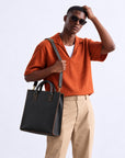 Modern black leather tote bag for men with dual top handles, contrast stitching and adjustable shoulder strap for work and business
