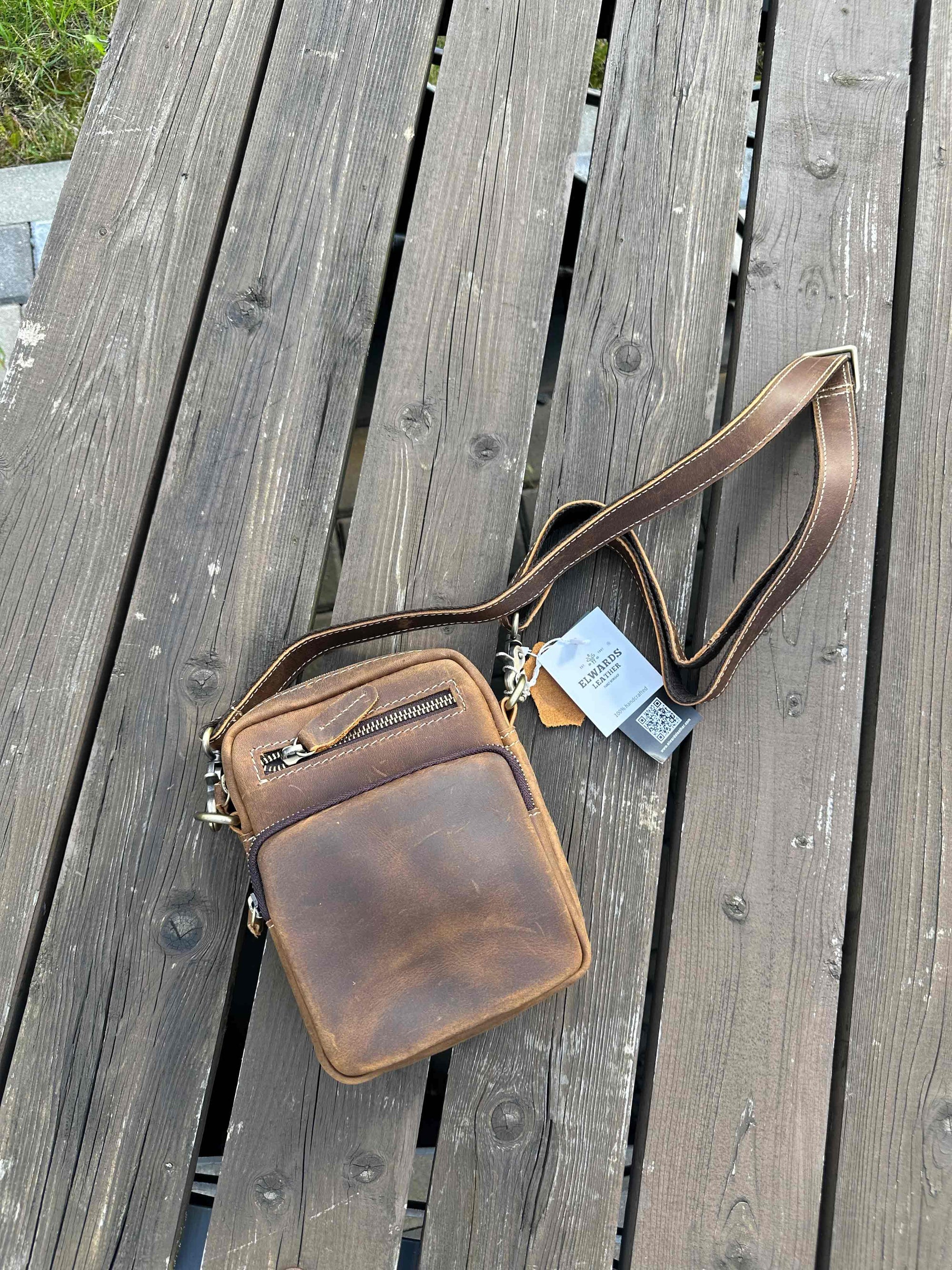 Brown leather crossbody bag on a wooden surface
