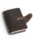 Open dark brown leather card holder with two brass button closures, showcasing soft suede interior.