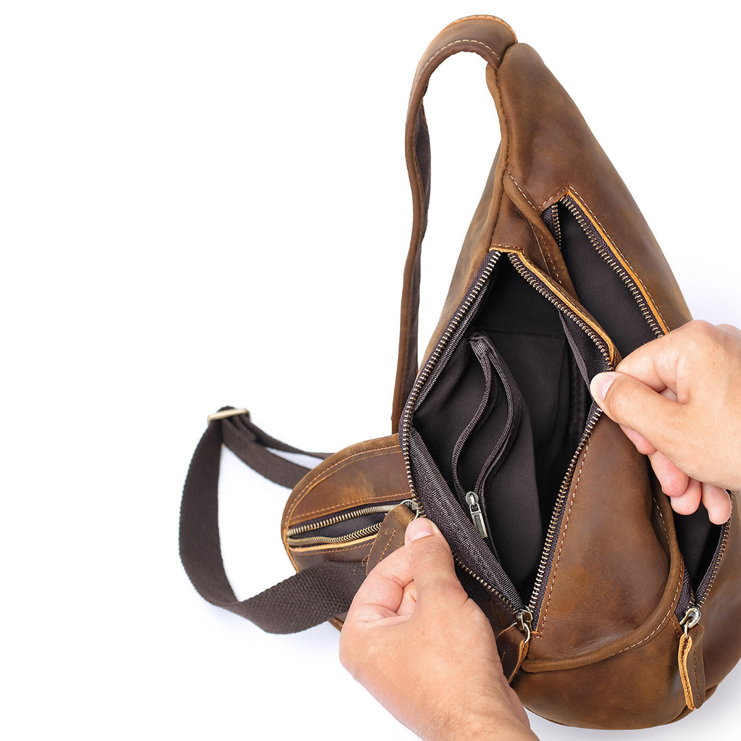 Brown leather bag with a hand opening it on a white background