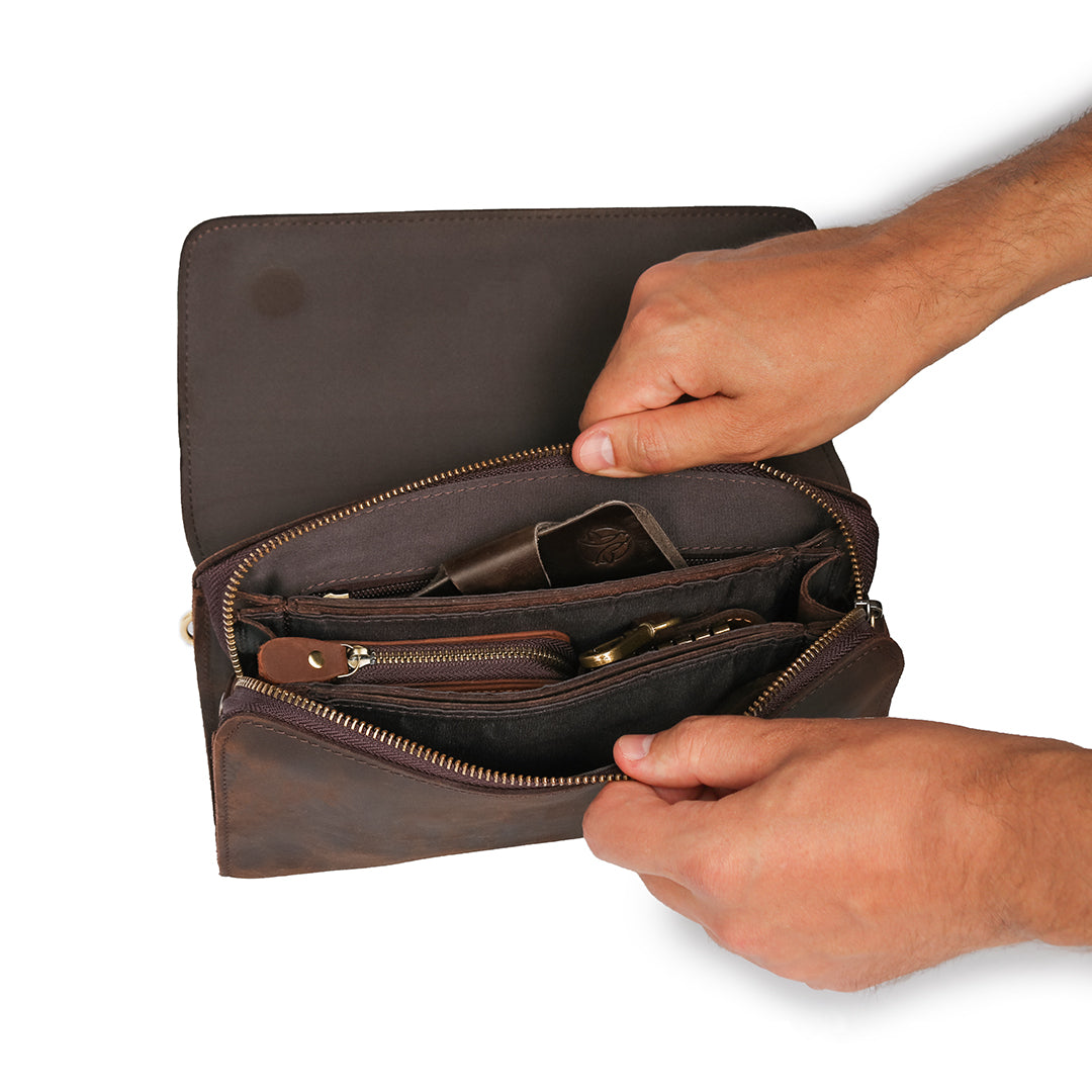 Interior of a men&#39;s dark brown leather clutch filled with accessories, showcasing its practicality and spacious compartments.