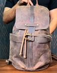 Detailed demonstration of a brown leather backpack, showcasing its compartments, durable hardware, and vintage finish.