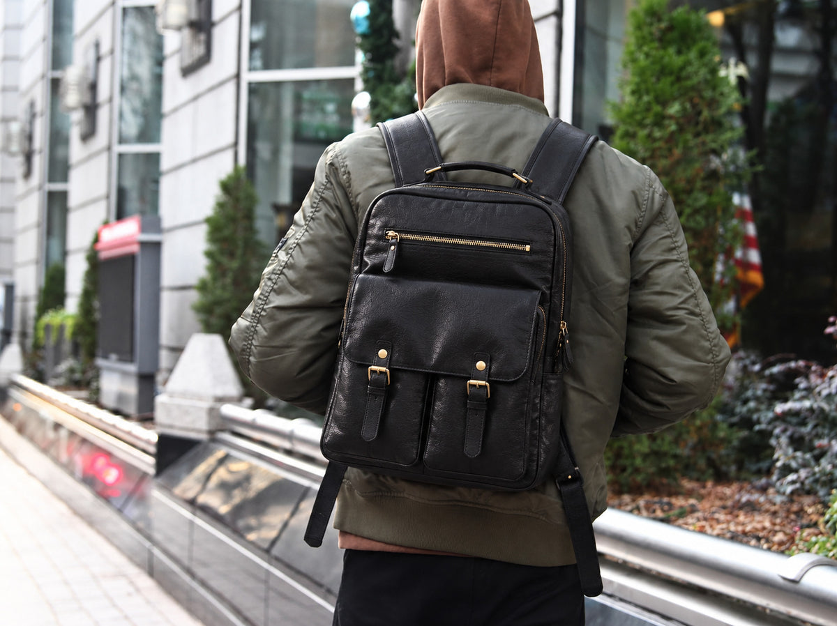 Professional black leather backpack for men with multiple front pockets, gold-tone zippers and padded straps for business and travel