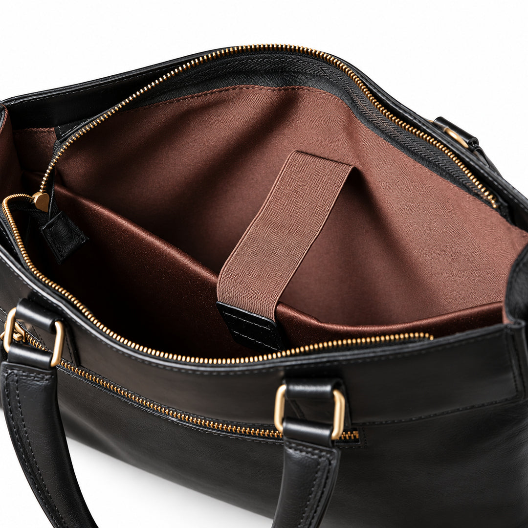 The black leather briefcase interior shows a wide brown sleeve with a retaining strap and black leather end tab.