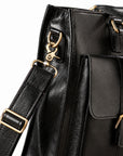 A close-up of the black leather briefcase shows the shoulder strap clasp, D-ring, adjustment buckle and stitching.