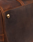 Protective brass feet on the bottom of a handcrafted leather travel bag for long-lasting use.