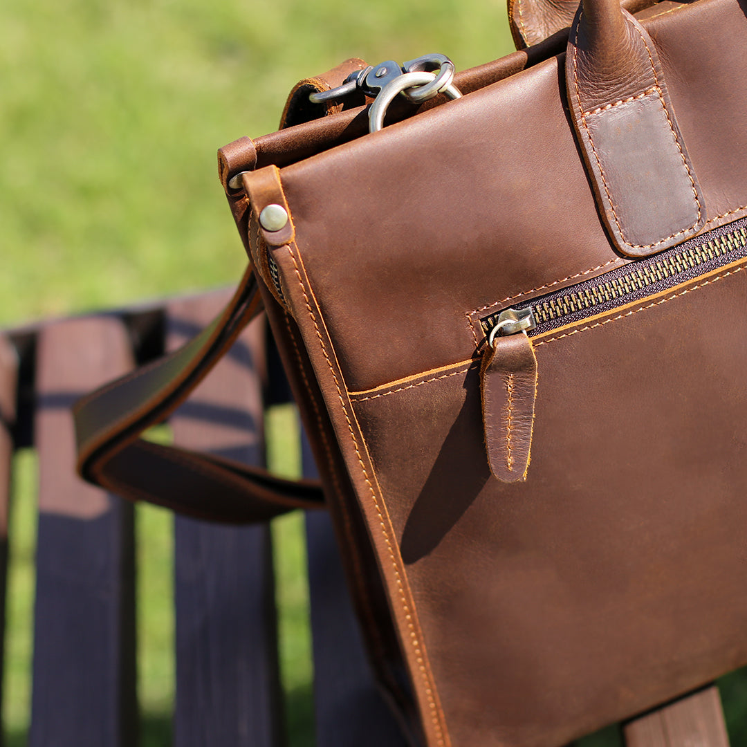 Rear view of brown leather men&#39;s bag with detailed stitching and vintage zipper design.