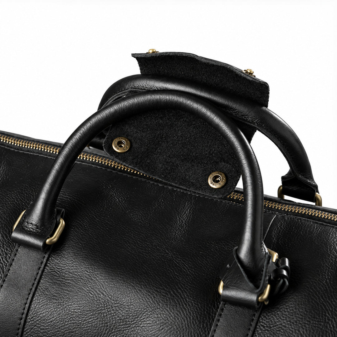 Refined black full-grain leather duffel bag handles with an open snap-fastened leather grip