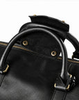 Refined black full-grain leather duffel bag handles with an open snap-fastened leather grip