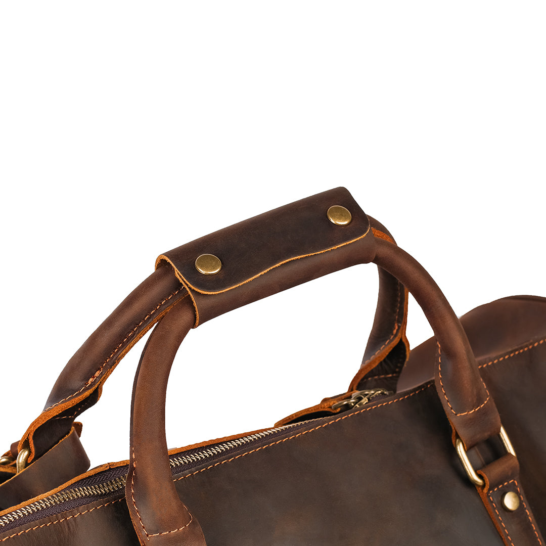 Close-up of reinforced leather handles on a vintage-style travel bag, ensuring comfortable carrying.