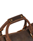 Close-up of reinforced leather handles on a vintage-style travel bag, ensuring comfortable carrying.