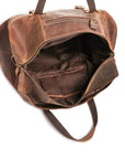 Close-up of reinforced brass rivets and stitching on vintage leather travel bag, ensuring durability and style.