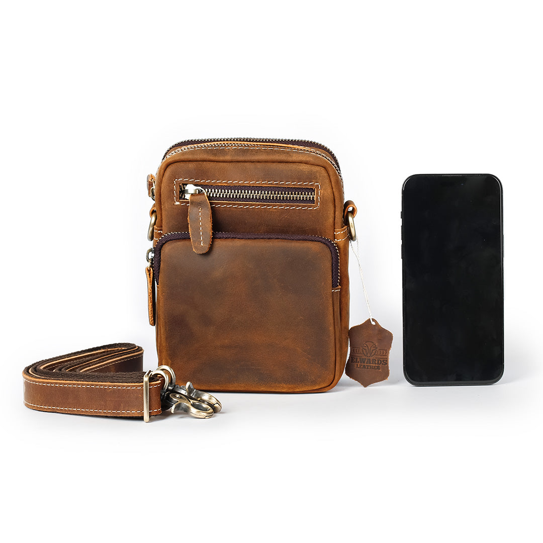 Brown leather crossbody bag with a smartphone on a white background