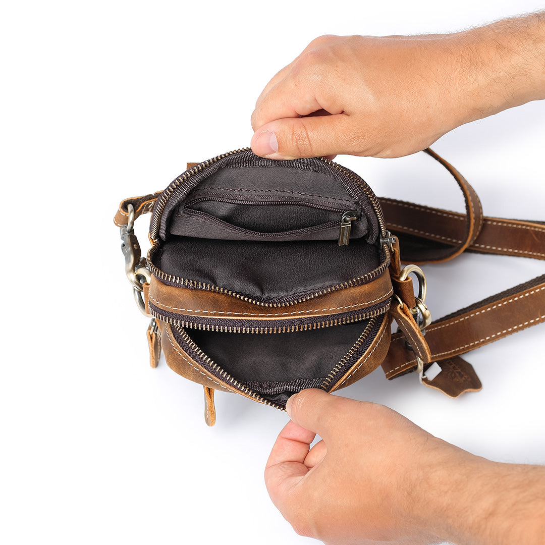 Brown leather bag with a hand opening it on a white background