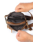 Brown leather bag with a hand opening it on a white background
