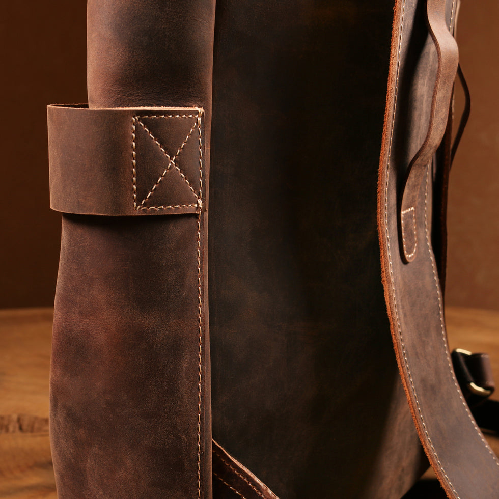 Close-up of a side pocket on a vintage brown Crazy Horse leather backpack with sturdy stitching and reinforced leather.