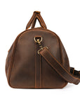 Side view of a brown Crazy Horse leather duffle bag with an attached adjustable strap for versatile carrying.