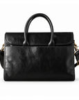 A black full-grain leather briefcase is shown from the front with a closed flap, rounded handles and a plain exterior pocket.