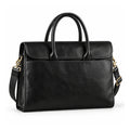 A black full-grain leather briefcase is shown at a slight angle with rolled handles, a rounded flap and a wide front slip pocket.