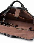 The open black full-grain leather briefcase reveals a brown sleeve with a retaining strap and a black leather end tab.