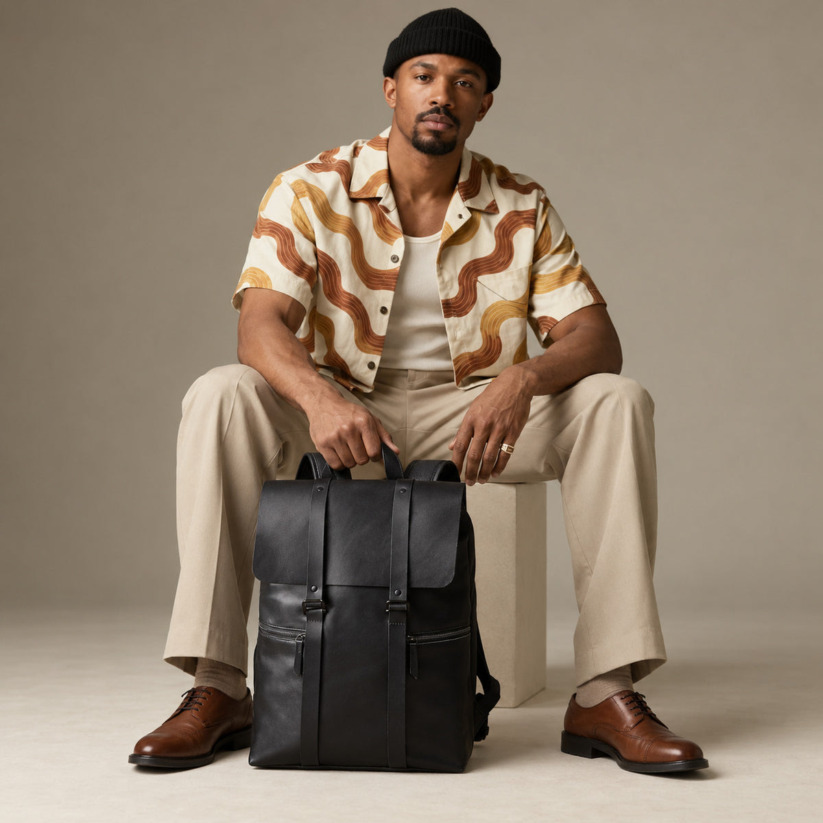 Sleek black leather backpack for men with structured flap closure, front zipper pockets and top carry handle