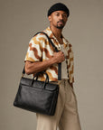 Slim black leather laptop briefcase for men with structured shape, dual carry handles and adjustable shoulder strap