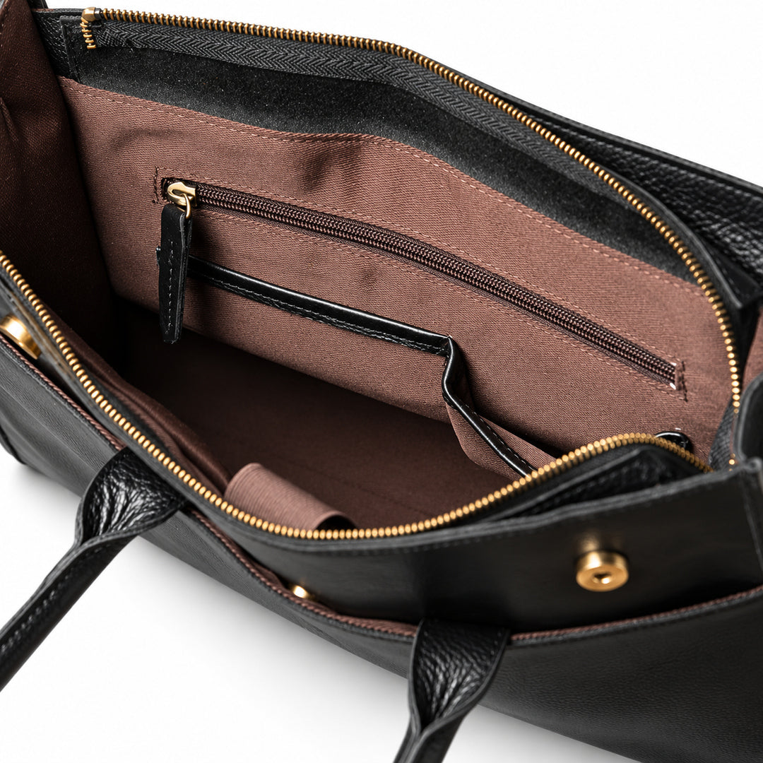 The black full-grain leather briefcase interior shows brown lining, a zipped wall pocket and two black-trimmed slip pockets.