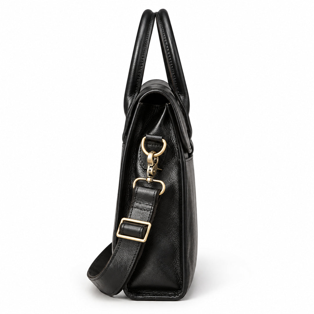 A side view of the black full-grain leather briefcase shows its narrow gusset, folded flap and adjustable shoulder strap.