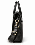 A side view of the black full-grain leather briefcase shows its narrow gusset, folded flap and adjustable shoulder strap.