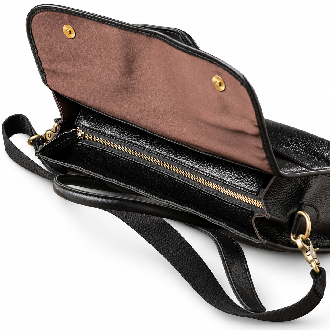 A top view of the black full-grain leather briefcase shows the closed main zipper beneath its brown-lined flap.
