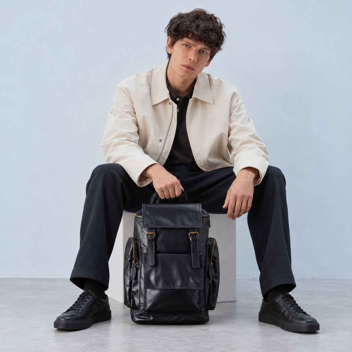 Spacious black leather travel backpack for men with buckle flap, multiple exterior pockets, top handle and adjustable shoulder straps