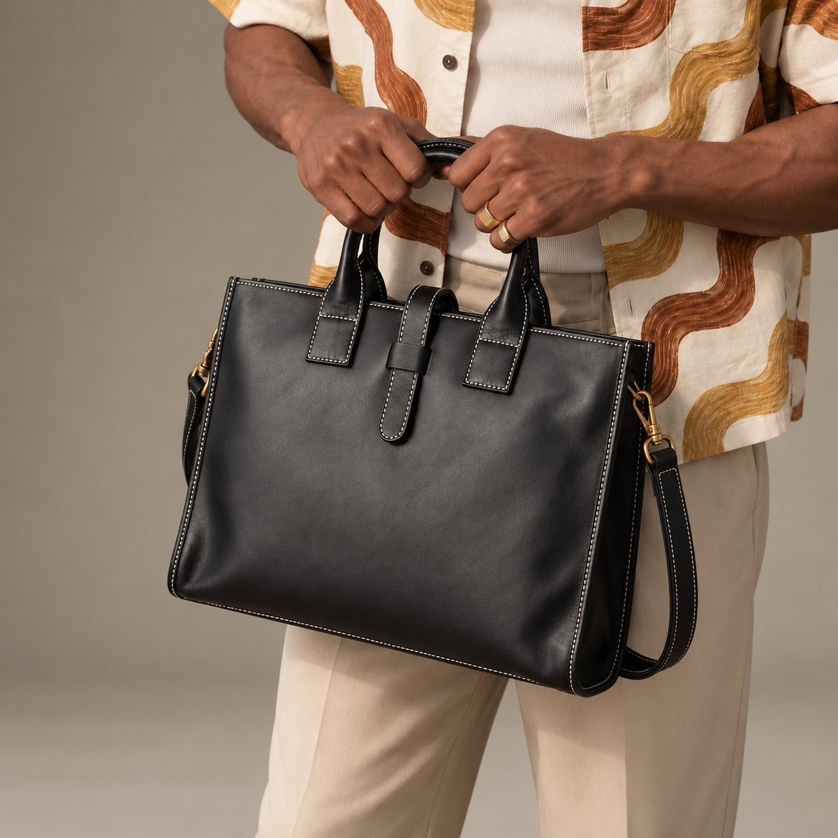 Structured black leather briefcase for men with top handles, contrast stitching, secure strap closure and detachable shoulder strap