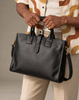 Structured black leather briefcase for men with top handles, contrast stitching, secure strap closure and detachable shoulder strap