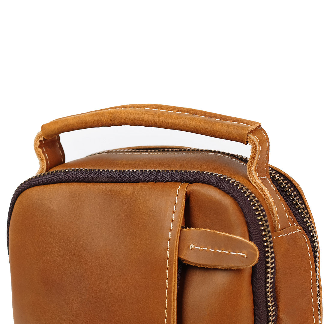 Close-up of tan leather crossbody bag with stitched top handle and zipper