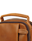 Close-up of tan leather crossbody bag with stitched top handle and zipper