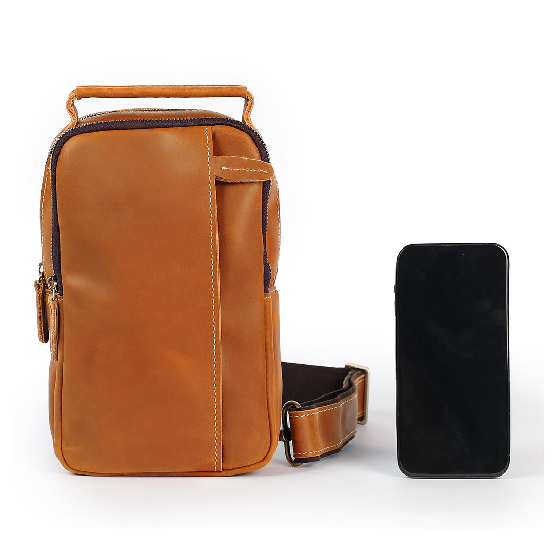 Compact tan leather sling bag shown next to smartphone for size comparison